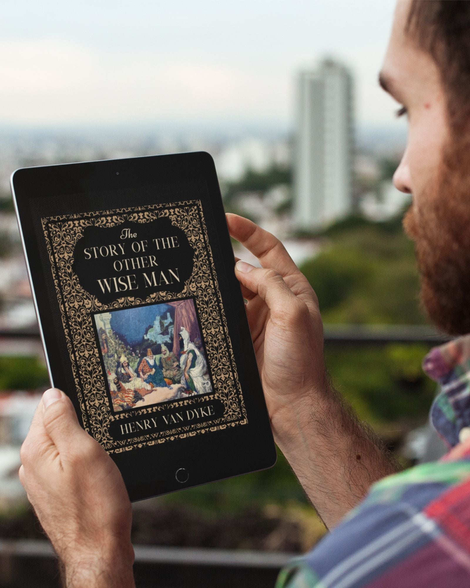 Bearded white man holding a black tablet on a balcony with buildings blurred in the background. On the tablet is the black and gold ornate cover of "The Story of the Other Wise Man".