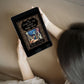 A dark haired woman holds a black tablet with the ornate black and gold cover of the ebook "The Story of the Other Wise Man."