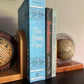 Globe bookends hold the paperback editions of Smidgen Press books, spines facing viewer. From left to right, "The Daisy Chain," "Frankenstein", and "The Voyagers".