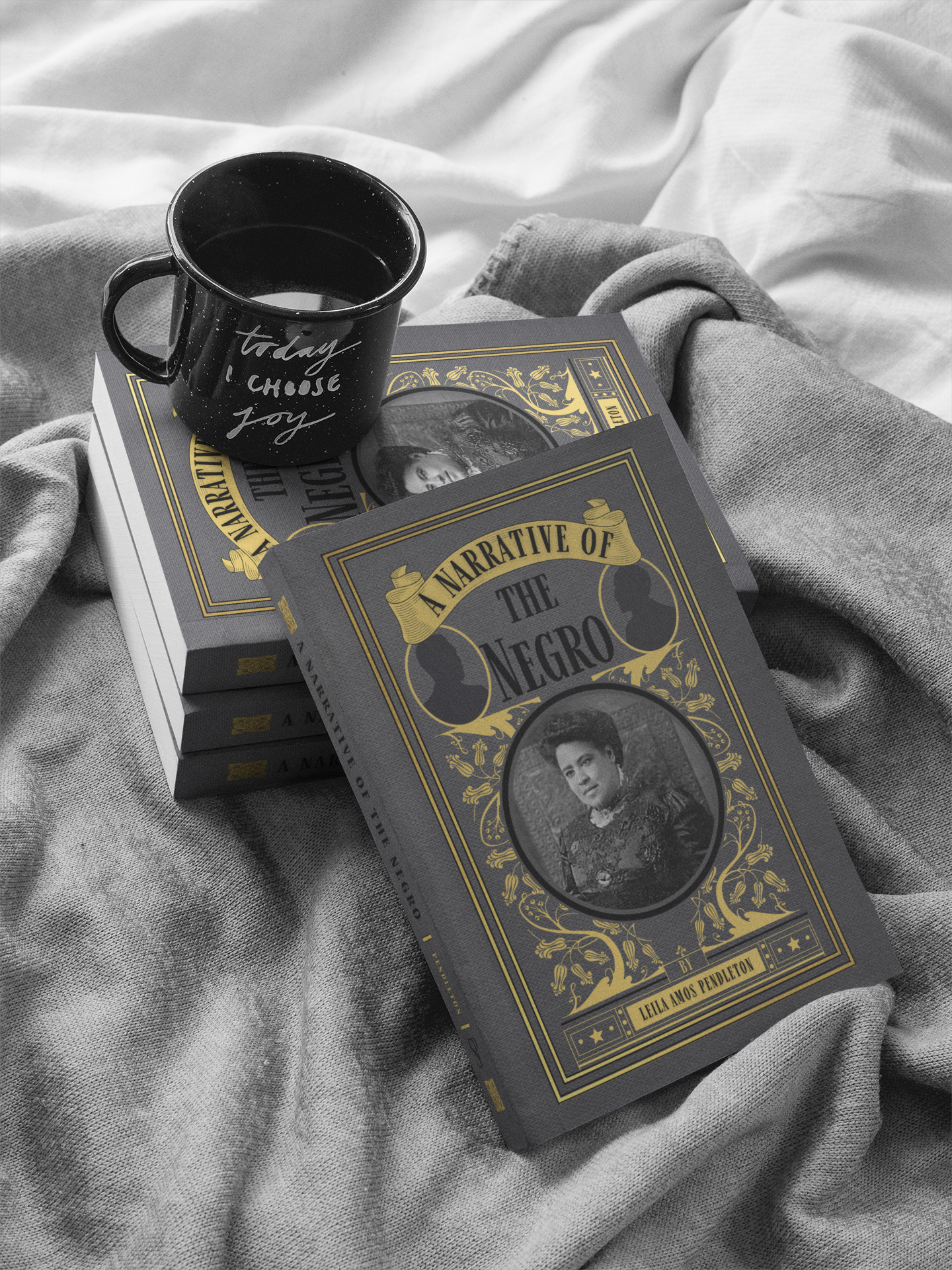 A stack of the paperbacks of A Narrative of the Negro, a yellow and grey book, stacked on a rumpled grey blanket with a dark coffee mug that says "today I choose joy". One paperback is propped up by the stack so that the cover is fully facing the viewer.